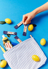 Hand reaching into a striped bag with popsicles and lemons on a blue background