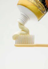 Close-up of a toothbrush with toothpaste being applied on a white background