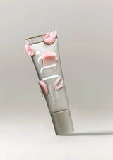 Lip balm tube with pink floral designs on a light gray background