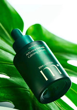 Green skincare serum bottle with dropper on a leaf background