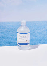 Bottle of toner with a blue label against a blue ocean background