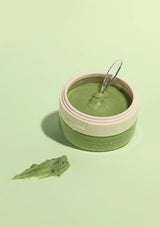 Jar of green cream with a spoon on a light green background
