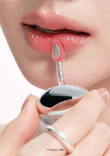 Close-up of a person applying lip gloss with a applicator.