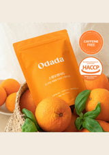 Orange package with 'Odada' branding surrounded by oranges on a light background