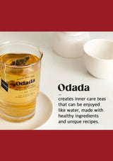 Glass of Odada tea with a tea bag, surrounded by white bowls on a light surface.