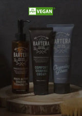 Barteria grooming products including a bottle, tube of cream, and tube of foam on a wooden surface with 'vegan' label.