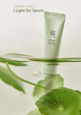 Skincare serum bottle with green leaves on a light background