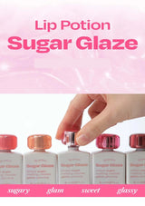 Lip Potion Sugar Glaze packaging with a hand picking up a bottle against a pink background