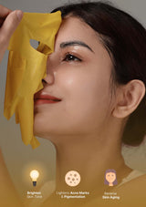 Woman with a yellow face mask applied to her face against a neutral background