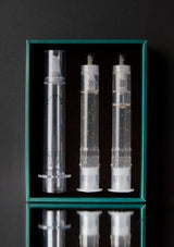 Three transparent syringes in a green box on a black background