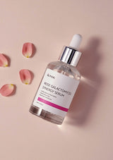 JUNIKA Rose Galactomyces Synergy Serum bottle with pink flower petals on a beige background