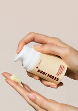 Hand holding a cream container labeled 'Soul 1988' with a beige background