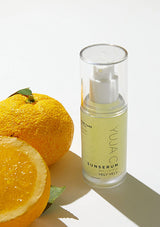 Skincare serum bottle labeled 'YUJA' with oranges on a light background