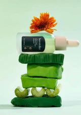 Stack of green soap bars with a bottle and orange flower on a light green background