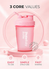 A pink ShakeBaby bottle shaker with a flip-top lid and integrated spoon, displayed on a pink pedestal with a whisker tool. The image includes marketing text reading '3 CORE VALUES' and feature icons for 'EASY TO USE', 'SIMPLE STRUCTURE', and 'FAST SHAKING'.
