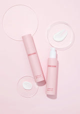 Two pink skincare bottles with a droplet of water on a light pink background