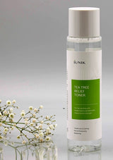 iUNIK Tea Tree Relief Toner bottle with a gray background and white flowers.