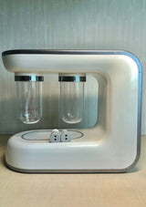 White electronic device with two transparent containers and a small round component on a light background