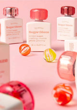 Three bottles of 'Sugar Glaze' with colorful nail art on a pink background