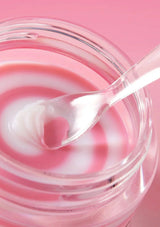 Pink and white swirled dessert in a glass bowl with a spoon on a pink background