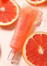 Pink skincare product with grapefruit slices on a light background
