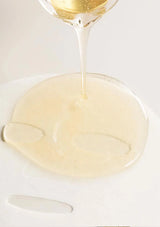 Glass of white wine being poured onto a white plate with a white background