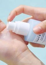 Hand applying skincare serum from a bottle with a light blue background