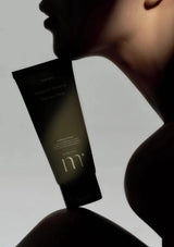 Tube of skincare product held by a person against a neutral background