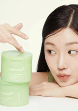 Woman holding a Medicube product with a plain background