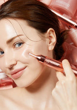 Woman applying a cosmetic serum to her face with a pink applicator.