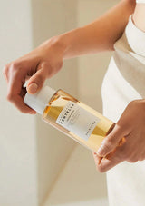 Person holding a bottle of skincare product with a neutral background