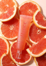 Pink lip balm tube labeled 'Chanel' on sliced grapefruits