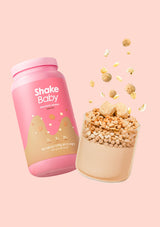 Pink 'Shake Baby' container with a glass of powder and toppings on a pink background