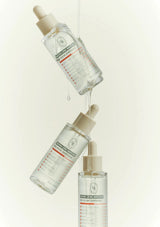 Three skincare serum bottles with droppers on a light beige background