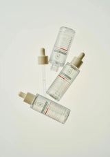 Four skincare bottles with droppers on a light background