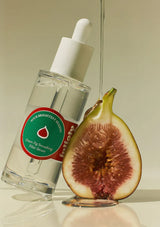 Skincare serum bottle with a fig and a dropper on a neutral background