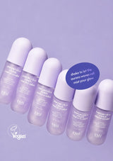 Six small roll-on bottles of Tangle Teezer Imply Eco Formula Hair Mist arranged diagonally on a light lavender background, with a blue circular callout and a white vegan logo.