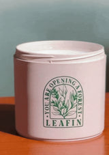 Pink container with 'LEAFIN' branding on a wooden surface and green background