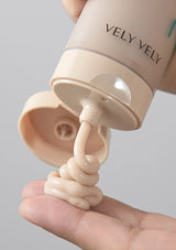 Hand holding a beige container of cream with 'VELY VELY' branding, showing cream being squeezed out.
