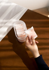 Hand holding a container of pink packets on a wooden surface