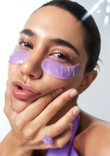 Woman wearing purple eye masks with a neutral background
