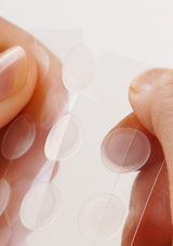Close-up of a hand holding a contact lens with a blurred background