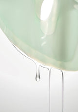 Close-up of a light green ceramic bowl with water droplets on a white background