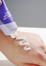 Person applying a white gel cream to their arm with a purple tube labeled 'NEWFASHION GEL CREAM'.