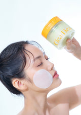 Woman applying a facial product with a jar labeled 'Clear Dea' on a white background