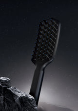 Black hairbrush on a rocky surface with a dark sky background
