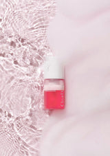 Red nail polish bottle with white cap on a light pink background