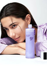 Woman with a bottle of Kumuzin skincare product on a white background