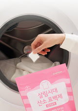 Person placing a white packet into a washing machine with a pink package labeled '氧白包' in front.