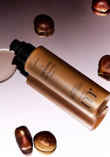 Cosmetic bottle with a brown shade on a reflective surface with chestnuts.